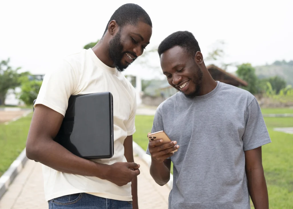 Two students sharing a smartphone outdoors.